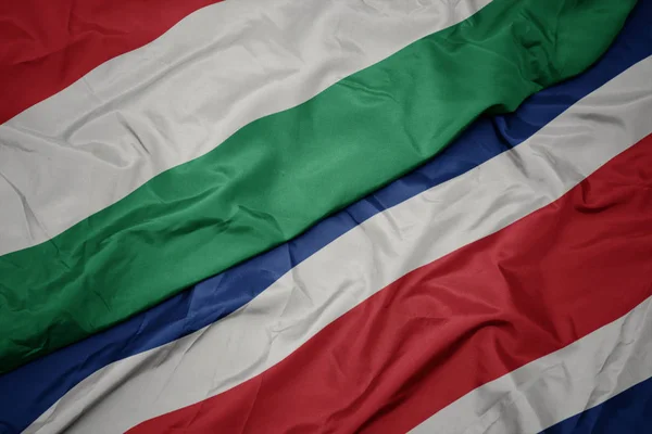 Vlnění barevné vlajky costa rica a státní vlajka Maďarska. — Stock fotografie