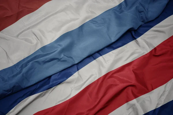 Zwaaiende vlag van Costa Rica en nationale vlag van Luxemburg. — Stockfoto