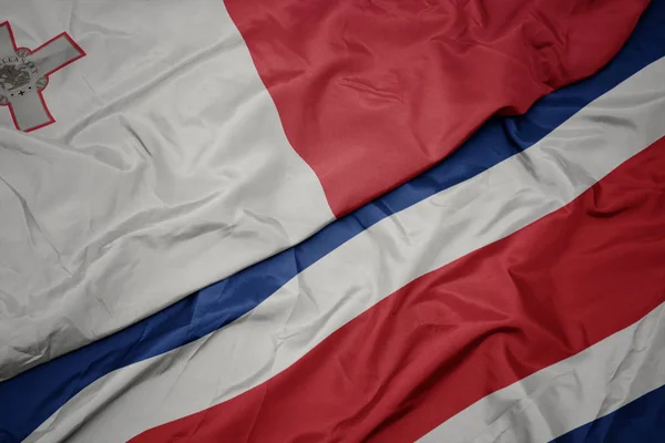 Zwaaiende vlag van costa rica en nationale vlag van malta. — Stockfoto