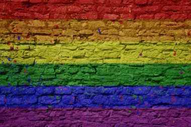 Büyük, eski tuğla bir duvarın üzerinde renkli, büyük, gay bir gökkuşağı bayrağı
