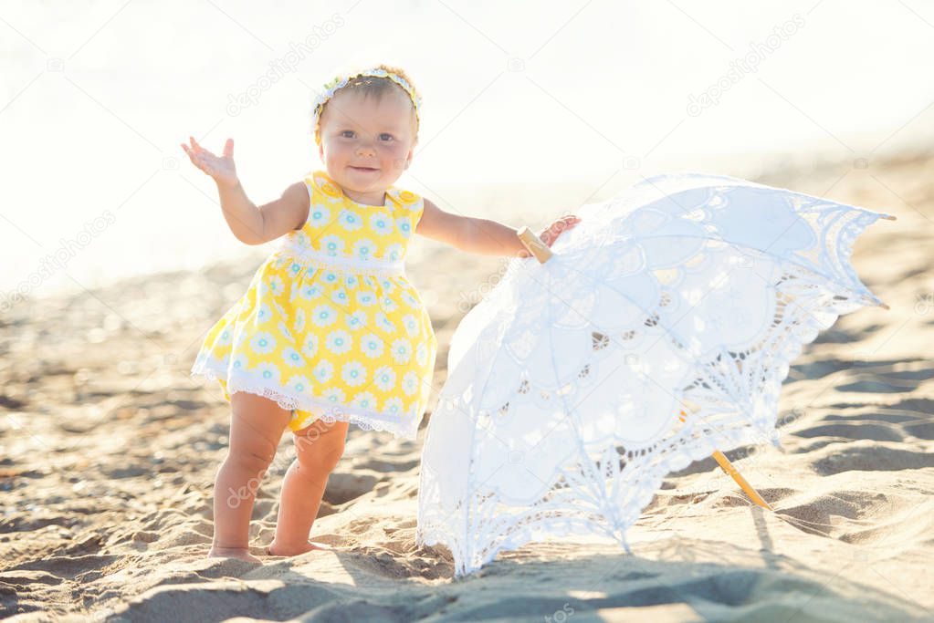 Lovely little girl on the beach with an umbrella