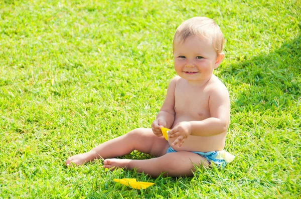 Kul stämning. Söt liten flicka sitter på gräset på en solig sommardag — Stockfoto