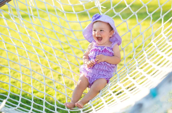 Tatil mutlu kız portresi. Hamak arka planı, küçük bir kız mor örgü içinde oturuyor
