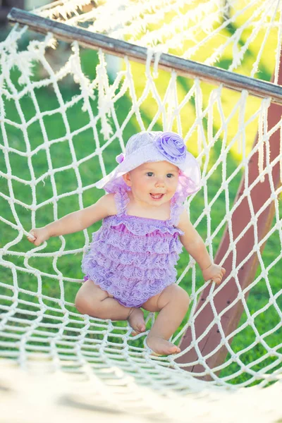 Tatil mutlu kız portresi. Hamak arka planı, küçük bir kız mor örgü içinde oturuyor