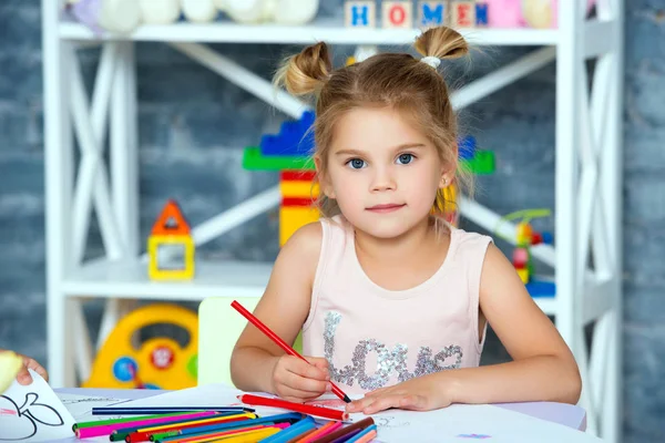 Маленька красива дівчинка малює різнокольоровими олівцями — стокове фото
