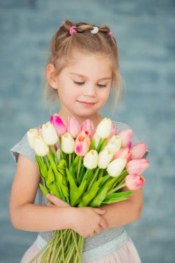 pencerenin yanındaki Lale ile gülümseyen sevimli küçük kız