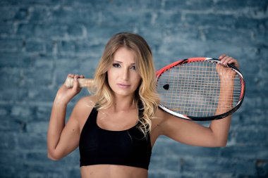 Bir raket ile güzel kız kız portresi, arka plan gri bir tuğla duvar.