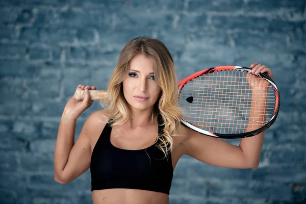 Bir raket ile güzel kız kız portresi, arka plan gri bir tuğla duvar.