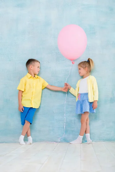 Jongenskind geeft een ballon aan een meisje. Tekenen van aandacht, sympathie en verkering. — Stockfoto