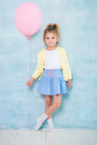 In voller Länge. niedliches kleines Mädchen mit einem rosa Luftballon auf blauem Hintergrund. — Stockfoto