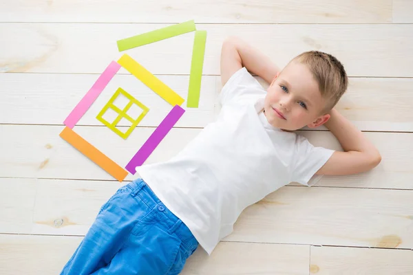 Bambino si trova sul pavimento accanto a una casa di carta colorata — Foto Stock