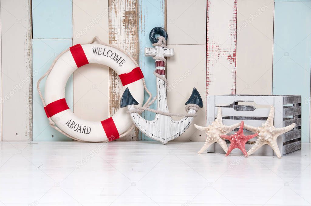 Composition on a marine theme with an anchor and life buoy, seashells and starfish on a wooden background.
