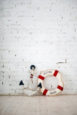 Bir deniz konulu bir kompozisyon bir çapa ve yaşam yüzüğü bir beyaz tuğla duvar ile