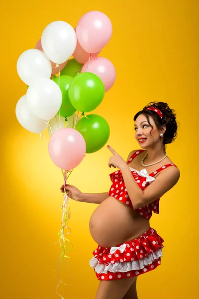 Zwangere Vrouw Met Ballonnen Een Gele Achtergrond Hij Kijkt Naar — Stockfoto