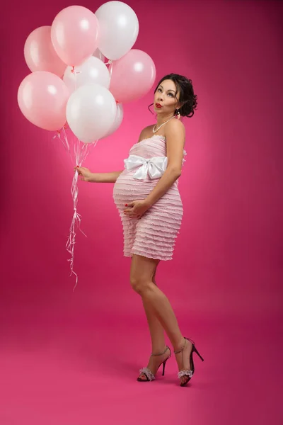 PIN Up ρετρό studio πλάνο του μια έγκυος γυναίκα με μπαλόνια. Φωτογραφία που λαμβάνονται στο στούντιο σε ροζ, φωτεινό φόντο — Φωτογραφία Αρχείου