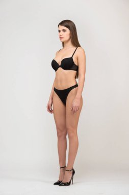 Tam uzunlukta portresi üç çeyrek güzel esmer kadınlar withslim şekil siyah sütyen ve şort. Beyaz arka plan üzerinde stüdyoda modeli yerine oturana.