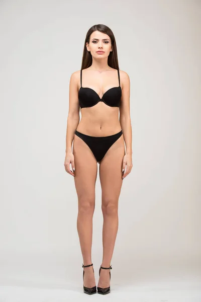 Önden Görünüm tam uzunlukta ince rakam siyah sutyen ve şort ile güzel esmer kadın portresi. Beyaz arka plan üzerinde stüdyoda modeli yerine oturana.