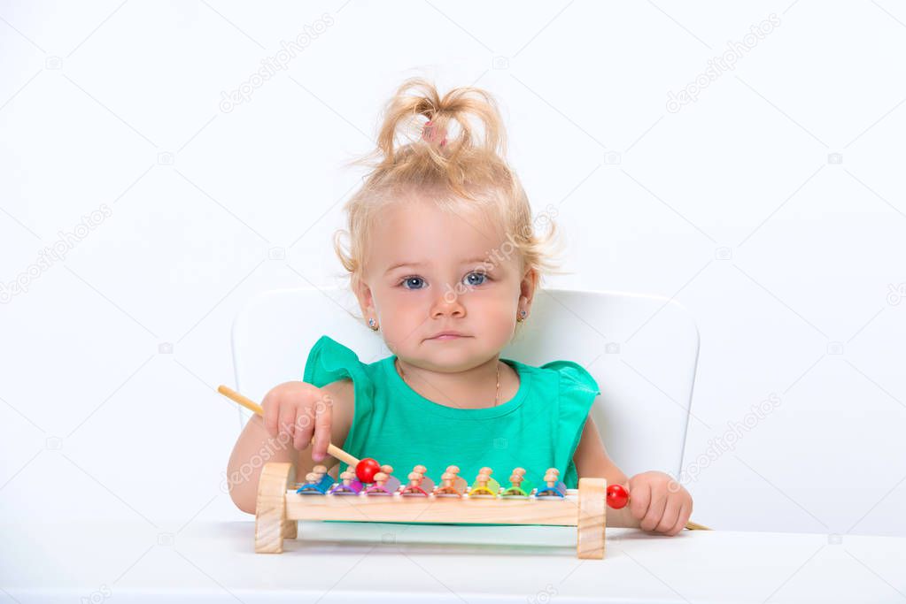 Cute smiling child little blonde baby girl playing with musical toy xylophone isolated on white background.