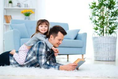 Mutlu bir aile ve babasının gün kavramı. Baba ile kızı harcama saat beraberlik evde. Sevimli küçük kız Baba'nın üzerinde geri sıcak yerde yatarken.