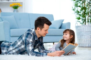 Sevimli küçük kız sıcak yerde birlikte, sevecen babası holding kitap, Aile Hobiler faaliyetleri evde yalan peri masalı okuma baba dinlerken.