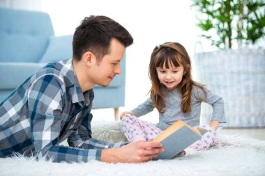 Sevimli küçük kız sıcak yerde birlikte, sevecen babası holding kitap, Aile Hobiler faaliyetleri evde yalan peri masalı okuma baba dinlerken.