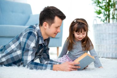 Sevimli küçük kız sıcak yerde birlikte, sevecen babası holding kitap, Aile Hobiler faaliyetleri evde yalan peri masalı okuma baba dinlerken.