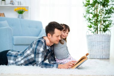 Sevimli küçük kız sıcak yerde birlikte, sevecen babası holding kitap, Aile Hobiler faaliyetleri evde yalan peri masalı okuma baba dinlerken.