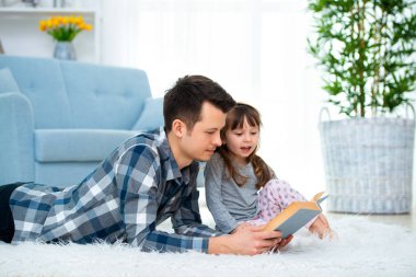 Sevimli küçük kız sıcak yerde birlikte, sevecen babası holding kitap, Aile Hobiler faaliyetleri evde yalan peri masalı okuma baba dinlerken.