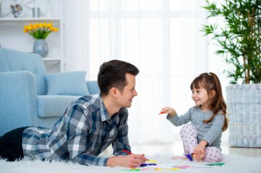 Baba ve kalite aile zaman birlikte evde olan küçük kız. Baba kız sıcak yerde ile çizim renkli yalan ile ucu kalem hissettim.