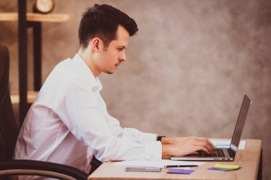 Ofis büro dizüstü bilgisayarda çalışarak, oturan genç Yöneticisi adam klavyede yazmaya konsantre.