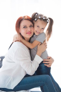 Sevgi dolu bir aile. Anne ve kızı oynuyorlar ve sarılıyorlar..