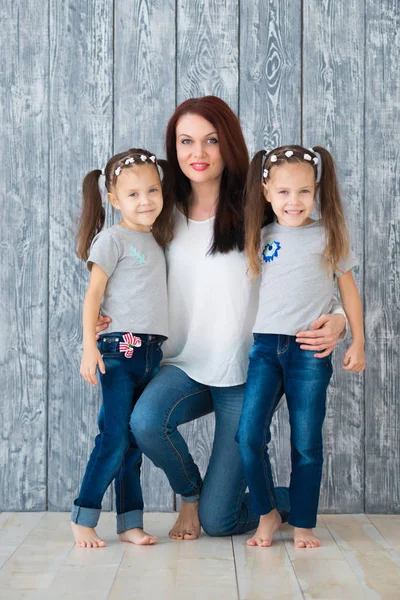 Mutter Und Zwei Zwillingsschwestern Auf Dem Hintergrund Einer Grauen Holzwand — Stockfoto