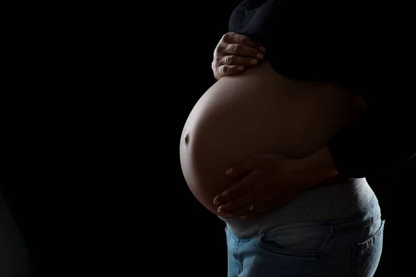 Close-up van zwangere buik op een zwarte achtergrond — Stockfoto