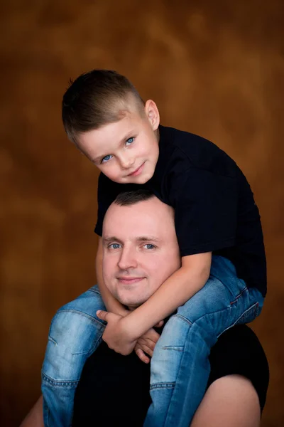 Padre e hijo pequeño. El chico está sentado en el cuello de su padre. Ambos sonríen. Abrazos familiares — Foto de Stock