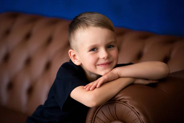 Kleine süße Junge Vorschulkind mit blonden Haaren sitzt auf dem Sofa, lo — Stockfoto