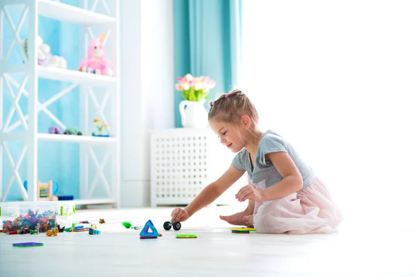 Little girl child playing with toys on warm floor indoors — Stock Photo, Image