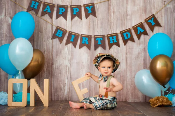 Feliz aniversário, pequeno cavalheiro O menino está vestido com um traje retro com suspensórios, um boné e um laço e senta-se entre os balões. Criança 1 ano — Fotografia de Stock