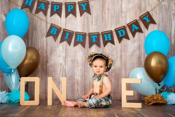 Happy birthday, little gentleman. The boy is dressed in a retro costume with suspenders, a cap and a bow tie and sits among the balloons. Child 1 year — Stock Photo, Image