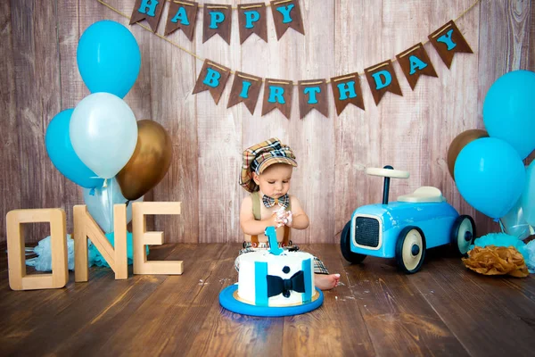 A sessão fotográfica esmaga o bolo para um cavalheiro. Fotozona decorada com um carro retro de madeira e balões de hélio. Feliz aniversário, 1 ano — Fotografia de Stock