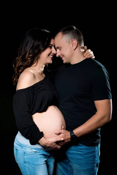 ハンサムな妊娠中のカップルの女と男の暗い黒い背景にポーズをとってします。家族愛と、赤ちゃんへの期待 — ストック写真