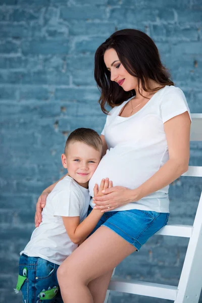 Zwangere moeder en zoontje jongen knuffelen buik. Gelukkig gezin en moederschap — Stockfoto