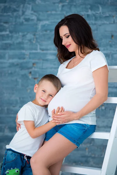 Zwangere moeder en zoontje jongen knuffelen buik. Gelukkig gezin en moederschap — Stockfoto