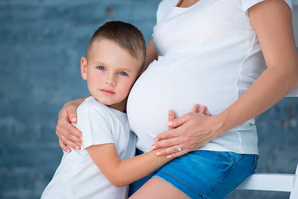 Terhes anya és kis fia fiú átölelve hasa. Boldog család és az anyaság — Stock Fotó