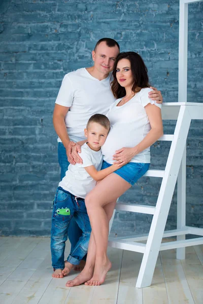 Pregnant father, son and fatherare standing and hugging near the stepladder. Happy family, childhood and parenthood — Stock Photo, Image