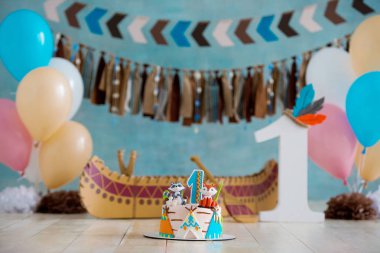 Decorated photo zone for 1 year Indian Apache chief with a canoe for a childrens party. First birthday and smash cake clipart