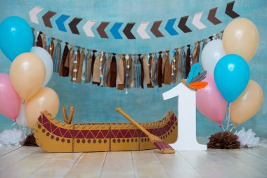 Decorated photo zone for 1 year Indian Apache chief with a canoe for a childrens party. First birthday and smash cake clipart