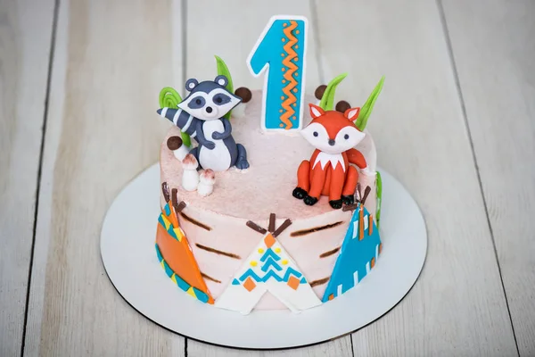 Primer plano de la torta de pastelero para cumpleaños bebé de 1 año de  edad. Pastel de niños está decorado con figuras de animales, wigwam y  número uno: fotografía de stock ©