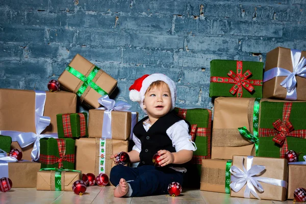 Pequeño bebé sonriente Santa Claus en sombrero de Navidad y traje de negocios. Feliz año nuevo y feliz Navidad. Vacaciones y regalos para niños —  Fotos de Stock