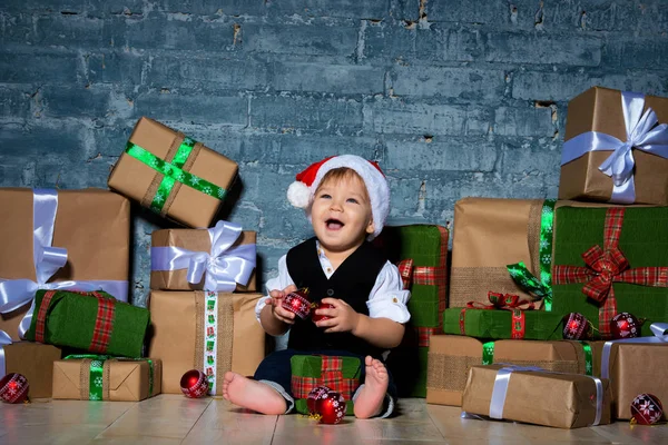 小微笑的婴儿圣诞老人在圣诞节的帽子和商务套装。新年快乐, 圣诞快乐。给孩子们的假期和礼物 — 图库照片