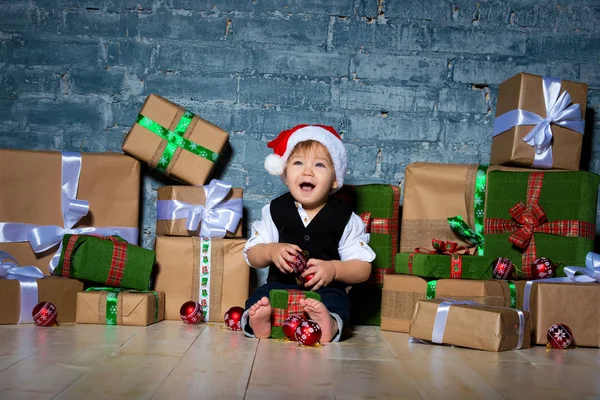 Piccolo bambino sorridente Babbo Natale in cappello di Natale e abito da lavoro. Buon anno e buon Natale. Vacanze e regali per bambini — Foto Stock